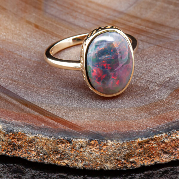 Bezel Set with a Filigree Design is an Australian Semi-Black Crystal Opal Ring in Yellow Gold by World Treasure Designs